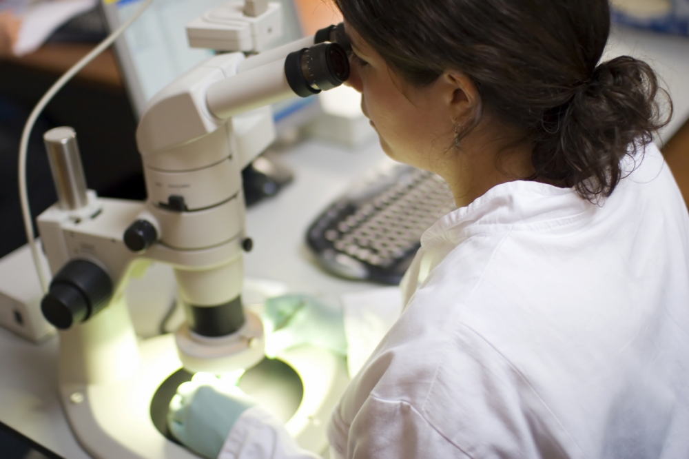 Woman in laboratory inspecting indoor air quality samples under a microscope